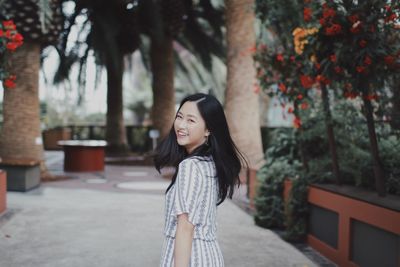 Portrait of smiling young woman standing at park