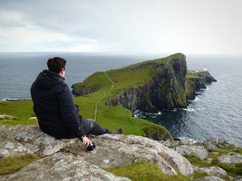 Man sitting on rock at seaside