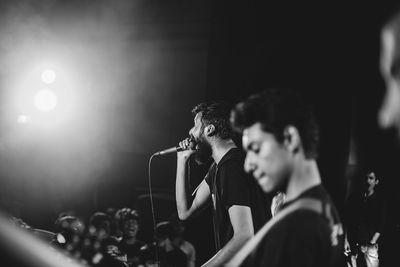 Side view of young, good looking, bearded man, singing at live rock music concert