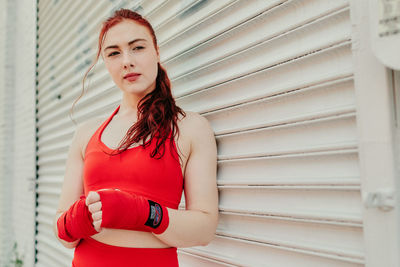 Portrait of woman standing against red wall