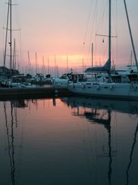 Sailboats moored in marina at sunset