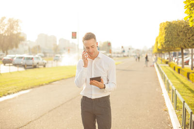 Full length of young man using phone on road