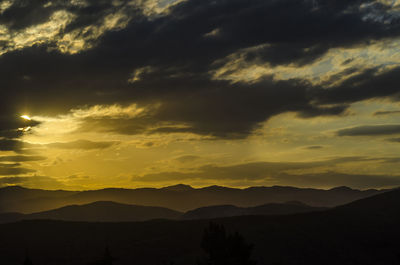 Scenic view of silhouette mountains against dramatic sky