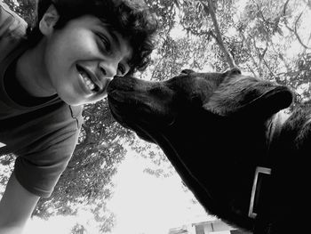 Low angle view of boy with dog against trees