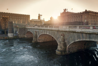 Arch bridge by historic buildings against sky