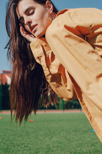 Young woman with closed eyes standing on soccer field