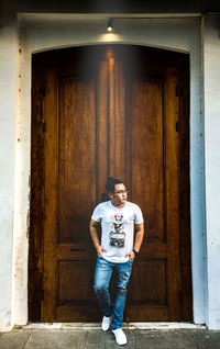 Young man standing against door