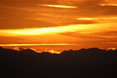 Scenic view of silhouette mountains against orange sky