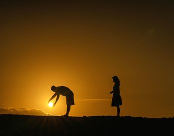 Silhouette friends standing against clear sky during sunset