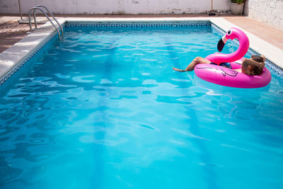 Man relaxing on inflatable raft in swimming pool