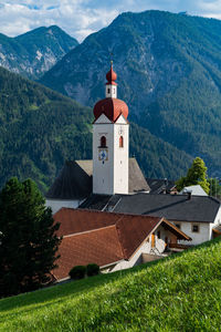 Lighthouse amidst buildings and mountains against sky