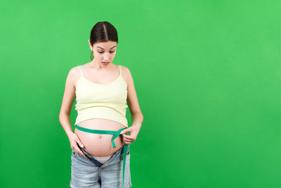 Young woman standing against green background