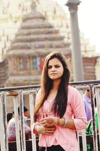 Beautiful young woman standing against railing