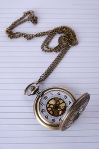 High angle view of pocket watch on paper