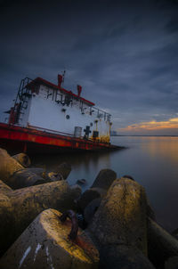 Abandoned ship moored on sea shore against sky