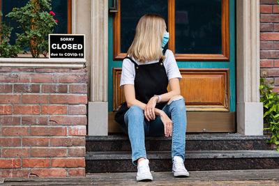 Full length of woman sitting on wall