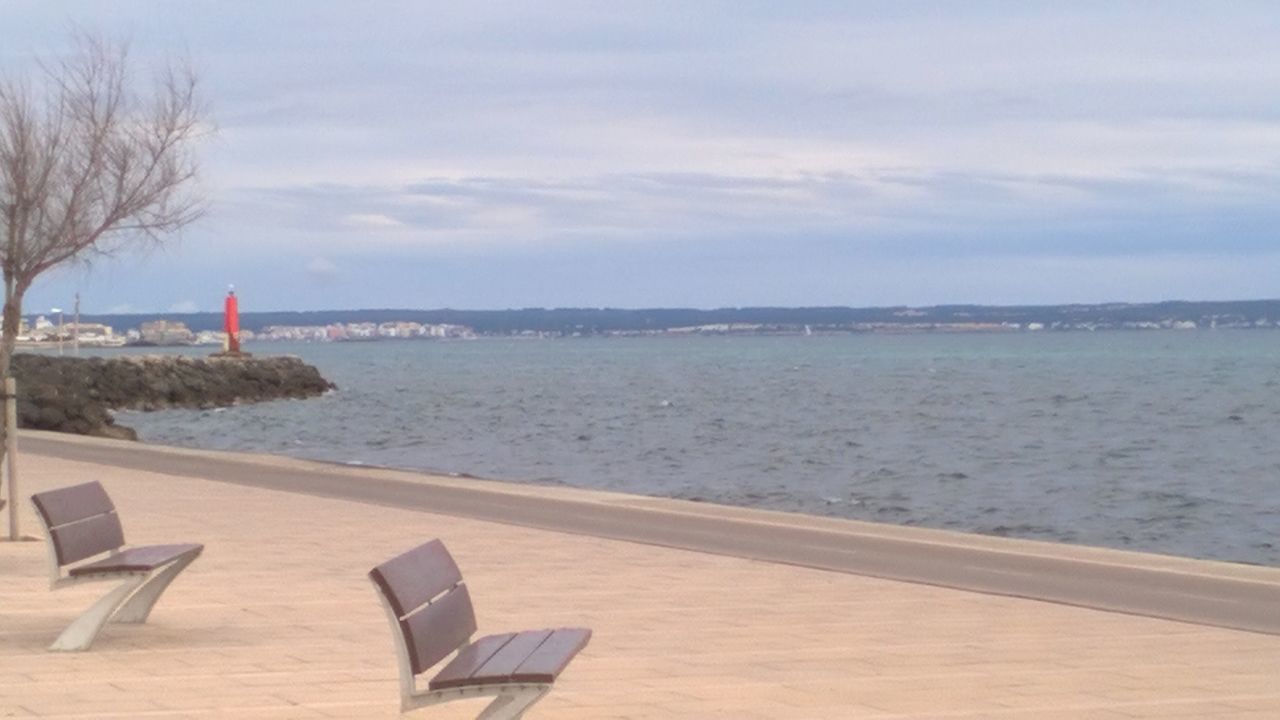 LOUNGE CHAIRS ON BEACH AGAINST SKY