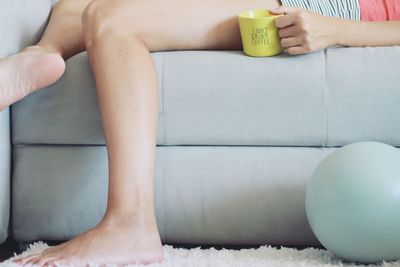 Low section of woman sitting on sofa at home