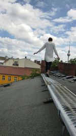 Full length of woman standing on road against cloudy sky