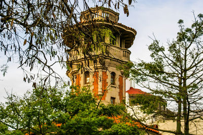 Low angle view of trees and building against sky