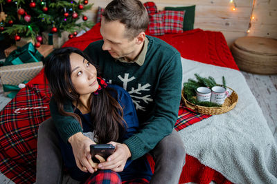 Young couple together spending christmas time in cozy home christmas tree