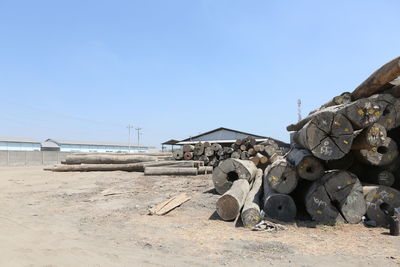 Stack of logs on field against clear blue sky