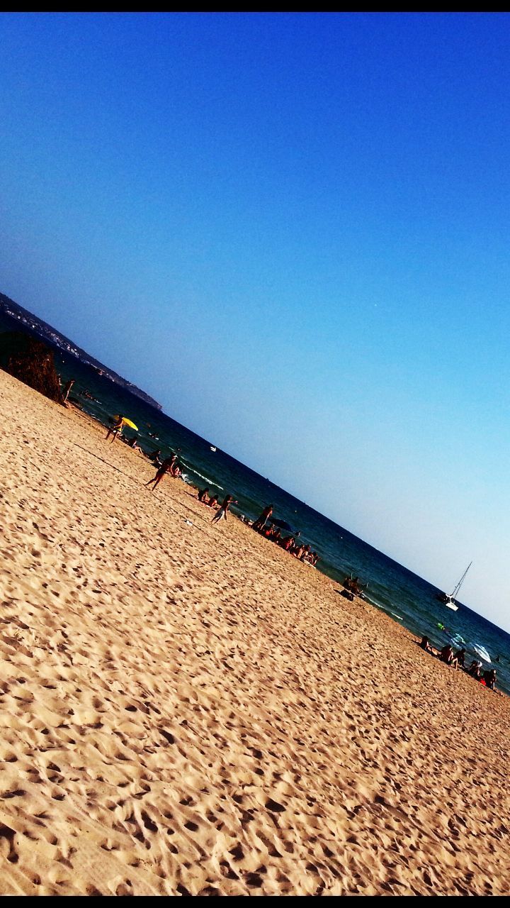 beach, sand, clear sky, blue, copy space, sea, shore, horizon over water, tranquility, tranquil scene, water, sunlight, nature, scenics, built structure, beauty in nature, day, outdoors, coastline, shadow