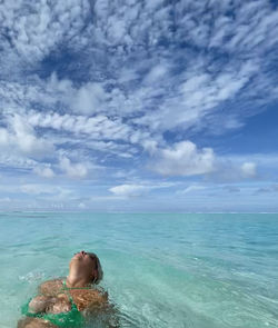 Man relaxing in sea against sky