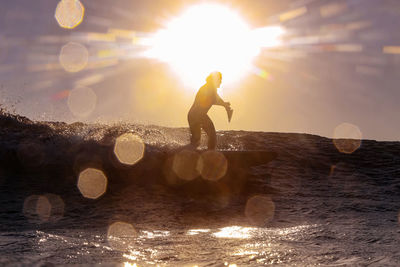 Silhouette man against sea against sky during sunset