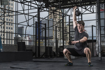 Man training with kettle bell at rooftop gym in bangkok