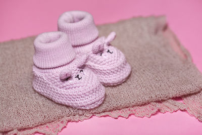 Close-up of baby booties and fabric against pink background