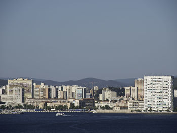 Buildings by sea against clear sky