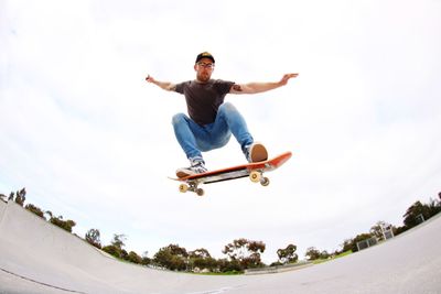 Low angle view of man jumping against sky