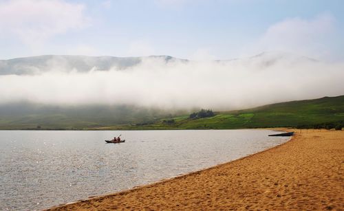 People canoeing on loch na fooey, sandy beach, green mountains, landscape of connemara,county galway