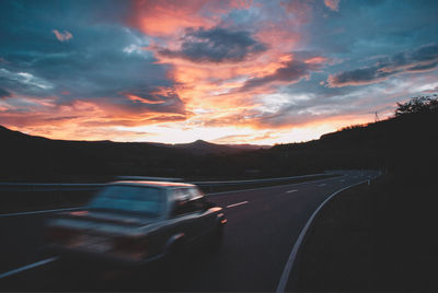 Cars on road against sky during sunset