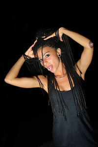 Portrait of young woman standing against black background