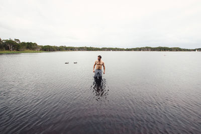 Man standing in lake against sky