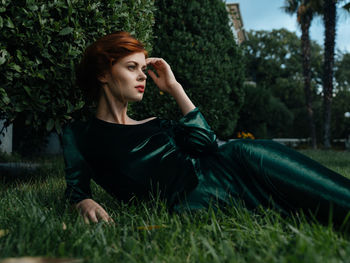 Young woman looking away while sitting on grass