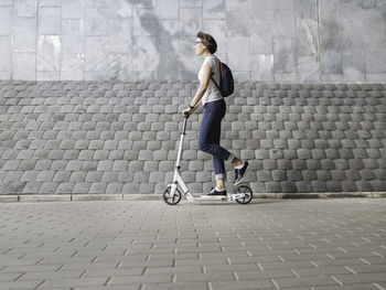 Woman rides kick scooter. female in jeans and sneakers. healthy lifestyle. eco-friendly  transport.