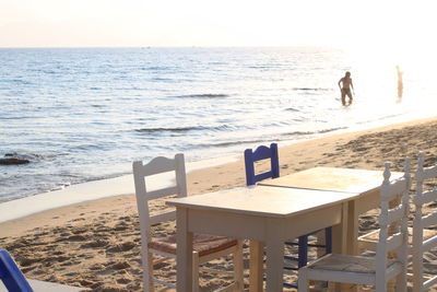 Chairs and table on beach against clear sky