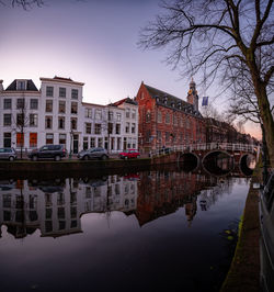 Reflection of buildings on river against sky in city