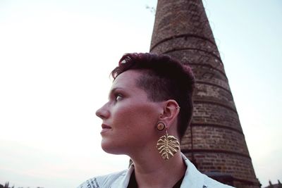 Portrait of young woman looking away against sky