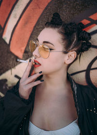 Close-up of young woman wearing sunglasses standing outdoors