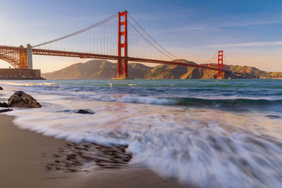 Suspension bridge over sea against sky