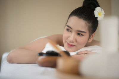 Smiling young woman lying on massage table in spa