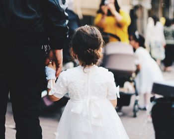 Rear view of girl in costume while standing with father on footpath