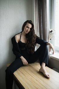 Young woman sitting on wall at home