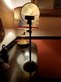 Close-up of electric lamp on table against wall