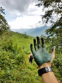 Close-up of hand on tree against sky