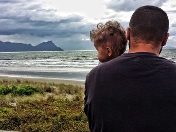 Couple sitting on beach against sky